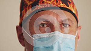 Male healthcare professional in a hospital operating theatre wearing a surgical cap and mask. Portrait of a physician or