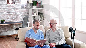 Male helper reading a book for old man