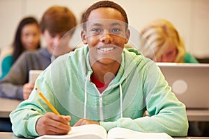 Male High School Student Studying At Desk In Classroom