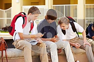 Male High School Students Using Mobile Phones On School Campus