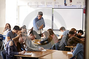 Male High School Teacher Standing By Interactive Whiteboard Teaching Lesson