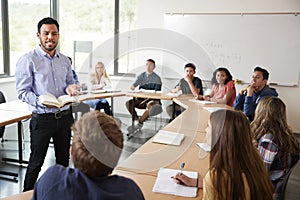 Male High School Tutor With Pupils Sitting At Table Teaching Maths Class