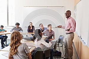 Male High School Tutor Standing At Whiteboard Teaching Class photo