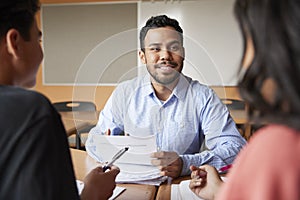 Male High School Tutor With Two Students At Desk In Seminar photo