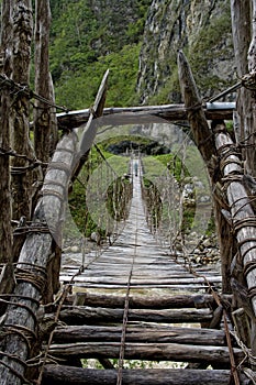 Male hiker crossing wooden fragile footbridge