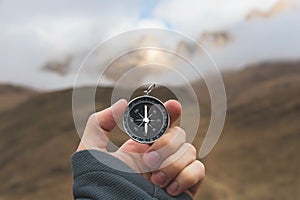 A male Hiker is looking for a direction with a magnetic compass in the mountains in the fall. Point of view shot. Man`s