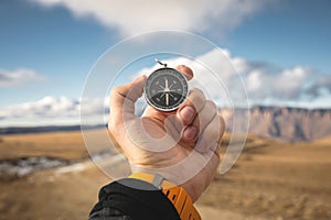 A male Hiker is looking for a direction with a magnetic compass in the mountains in the fall. Point of view shot. Man`s