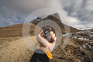 A male Hiker is looking for a direction with a magnetic compass in the mountains in the fall. Point of view shot. Man`s