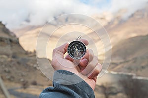 A male Hiker is looking for a direction with a magnetic compass in the mountains in the fall. Point of view shot. Man`s