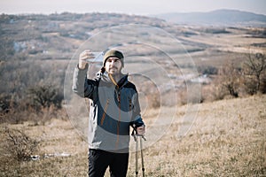 Male hiker making selfie while standing on a field