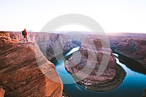 Male hiker overlooking Horseshoe Bend at sunset, Arizona, USA