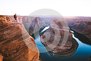 Male hiker overlooking Horseshoe Bend at sunset, Arizona, USA