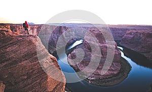 Male hiker overlooking Horseshoe Bend at sunset, Arizona, USA