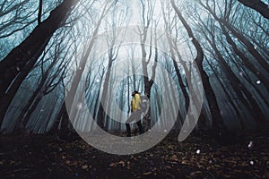 Male hiker standing in dark forest - Man with backpack walking in mystery woodland - Traveler in nature, courage, risk and success