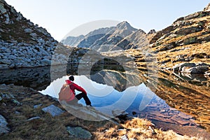 Male hiker takes a rest sitting next a mountain lake