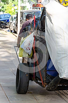 Male with his back dragging a homeless cart full of different bags and items