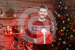 Male holding a big red ribbon gift box and smiling.