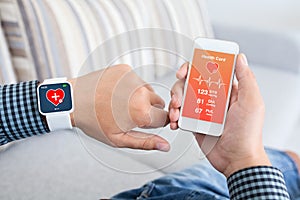 Male holding phone and smart watch with app health sensor