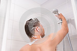 Male holding shower head with flowing water