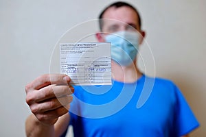 male is holding a vaccination record card and corona virus vaccine vials. Passport of immunity to the coronavirus in the hands of