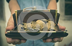 Male holding wallet with money gold coins in her hand