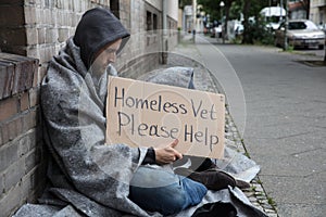 Male Homeless Sitting On A Street Asking For Help