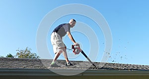 Male Homeowner Blowing Leaves from Gutter photo