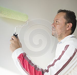 Male house painter worker painting and priming wall with painting roller