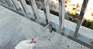 Male houseworker in gloves paints new railings on balcony