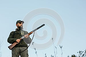 Male hunter holding a shotgun while searching for prey.