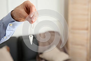 Male hypnotist with pendulum in office