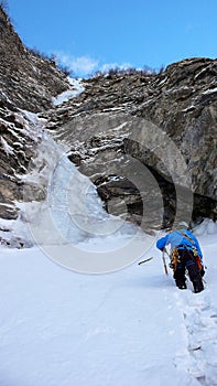 Male icci climber approaching an ice fall and couloir in the Swiss Alps