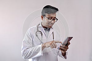 Male indian doctor in white coat and stethoscope touching smart phone