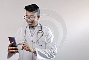 Male indian doctor in white coat and stethoscope touching smart phone