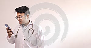 Male indian doctor in white coat and stethoscope touching smart phone