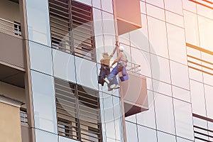 A male industrial climber washes the windows of a tall modern skyscraper