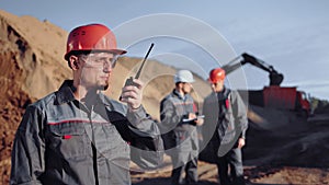 Male industrial engineer talking using walkie talkie at construction site medium shot