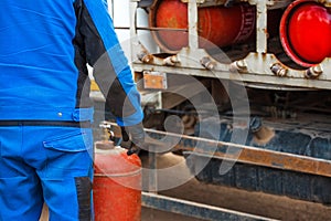 Male industrial worker puts a gas cylinder into a gas machine. Equipment for the safe transportation of propane gas bottles