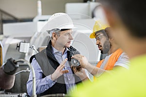 Male inspector having discussion with worker in metal industry