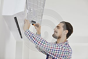 Male installer or repairman installs or repairs air conditioning inside apartment.