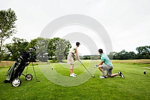 Male instructor assisting woman in learning golf