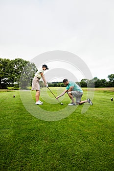 Male instructor assisting woman in learning golf