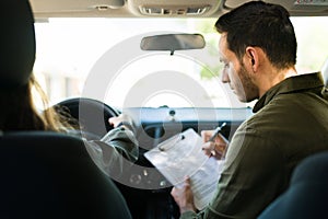 Male instructor checking the driving skills of a teen girl