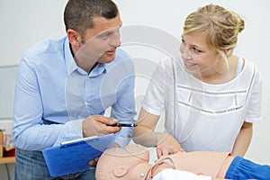 male instructor explaining cpr to student using dummy