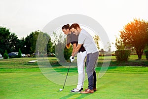 Male instructor showing woman to play golf