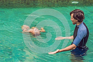 Male instructor swimming for children teaches a happy boy to swim in the pool