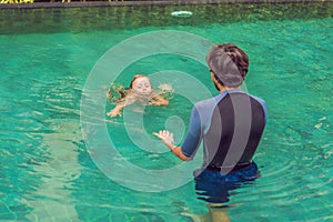 Male instructor swimming for children teaches a happy boy to swim in the pool