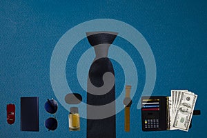 Male Items on a Blue Background Shot from Above with Glasses, Notepad, Money, Watches, Cologne, Charger and Headphones