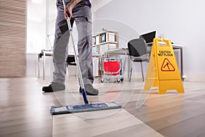 Male Janitor Cleaning Floor In Office