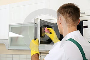 Male janitor cleaning microwave oven